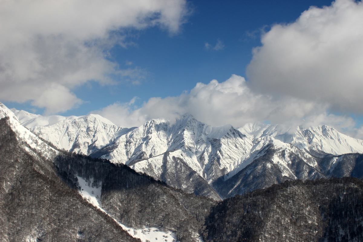 Snow-capped peaks above forested ridges in Gabala, Azerbaijan