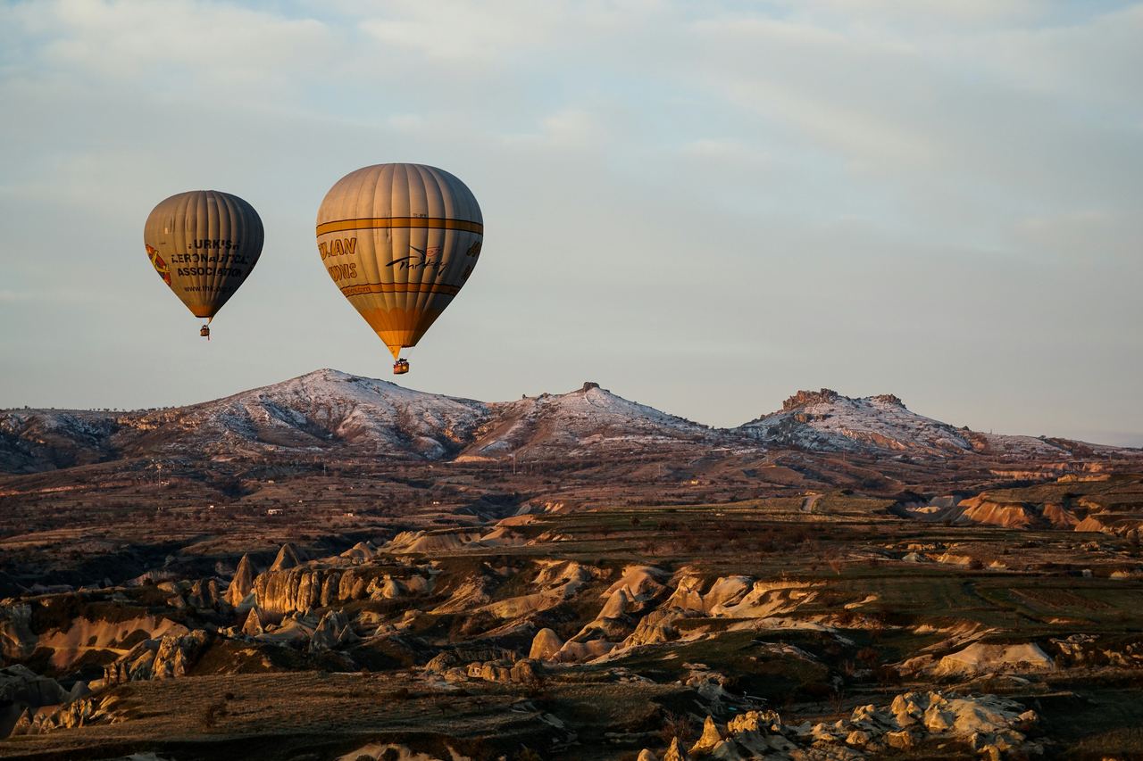 Hot-air balloons at sunrise over the valleys of Cappadocia, Türkiye